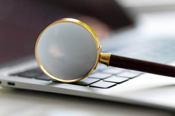 Photo d'une loupe en gros plan, posée sur un clavier d'ordinateur portable